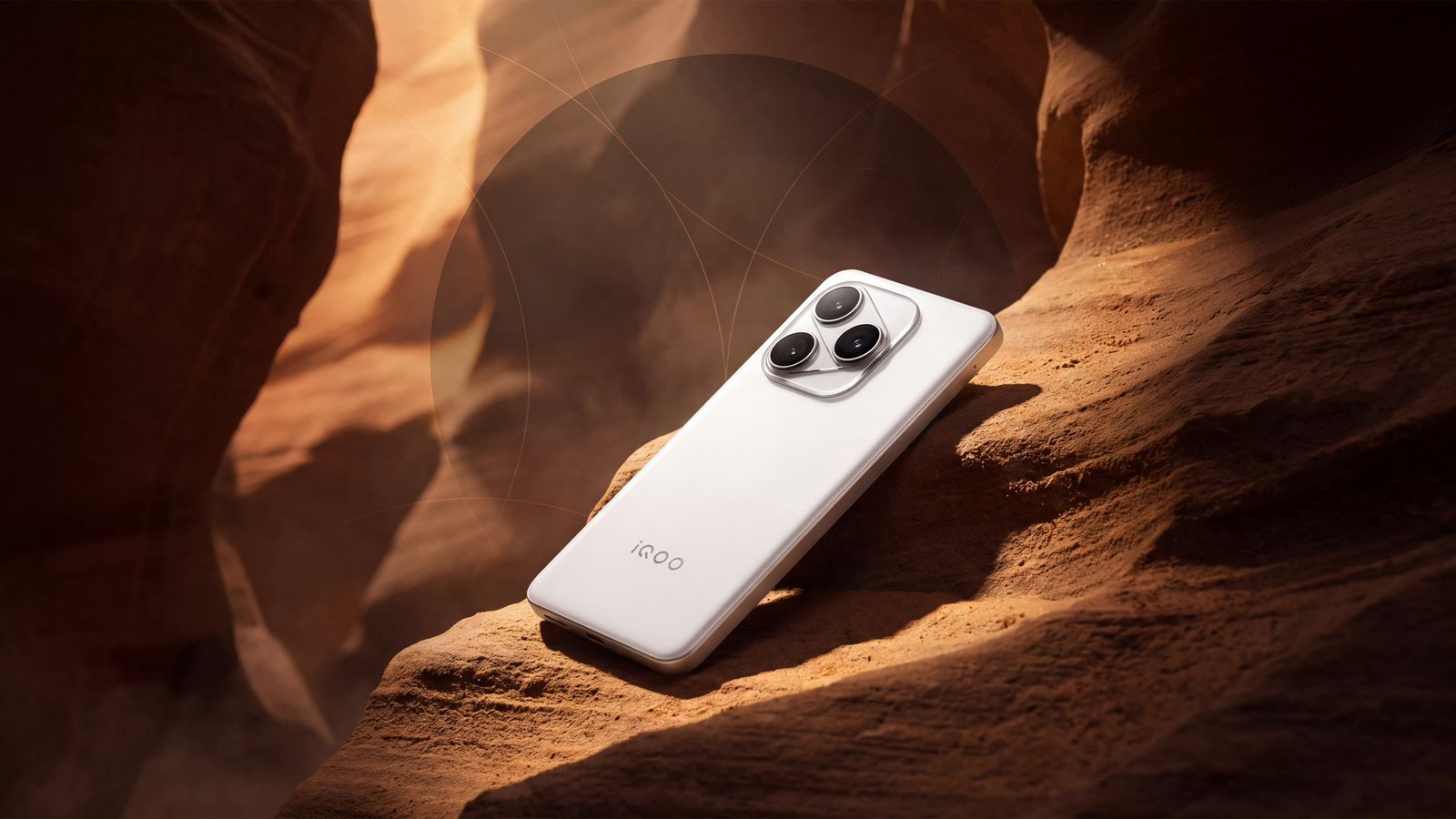 White smartphone lying face down on ochre rock in a narrow canyon crossed by low, warm light
